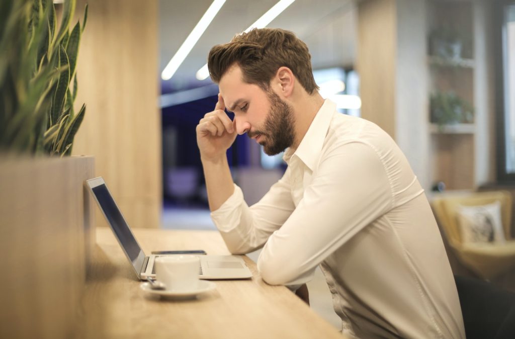 A male accountant, deep in thought, on his laptop 