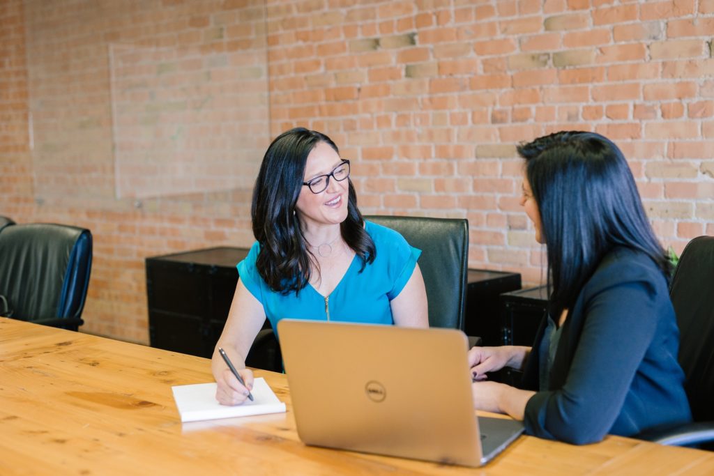 Two female accountants smiling and discussing work