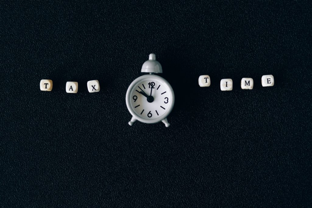 The words "tax time" against a black backdrop, next to a alarm clock