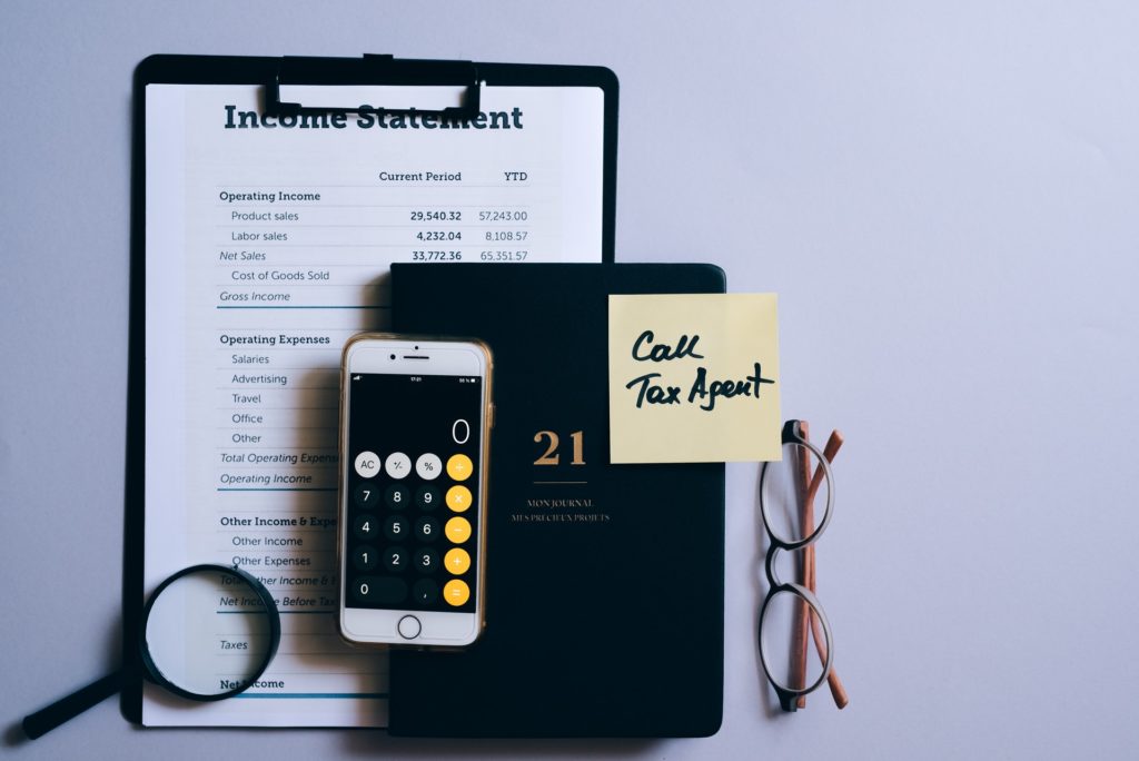 Income statement on a clipboard as well as a diary, mobile phone and note to call the tax agent