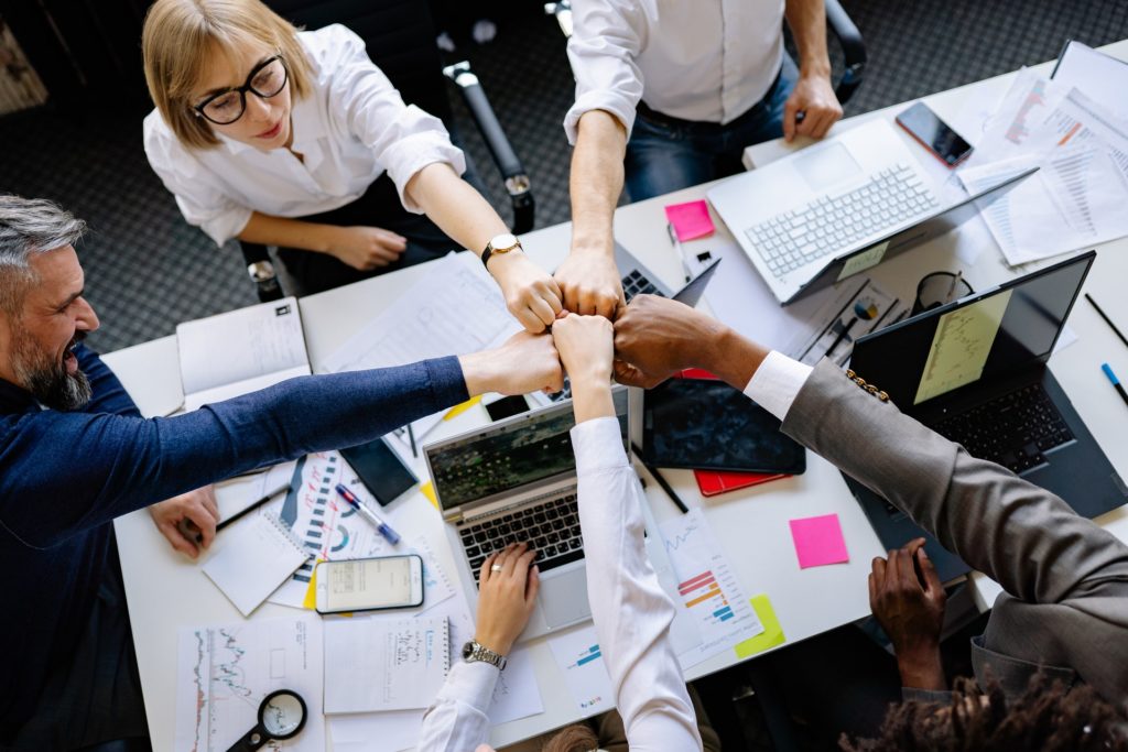 A group of work colleagues fist pumping around a table