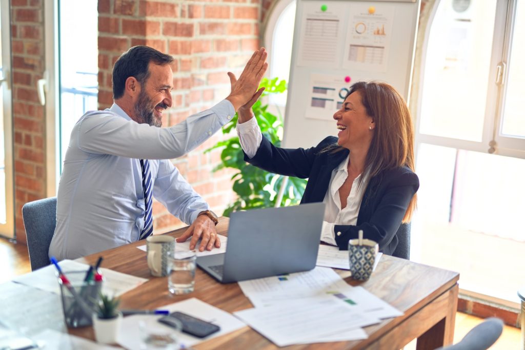 Two colleagues high fiving one another