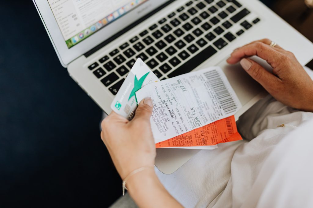 Person Using a Computer and Holding a Credit Card and Receipts