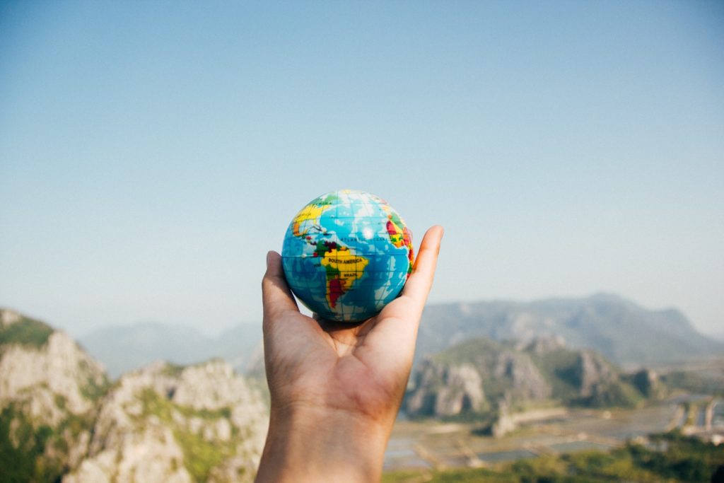 A man holding a small world globe in his hand