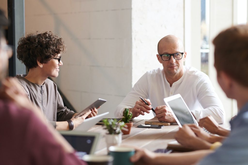 Photo of an employer sitting in front of his accounting team engaged in a discussion