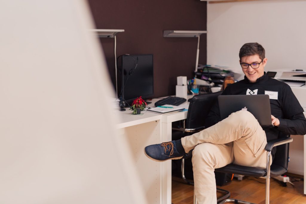 Young male accountant looking happy while he works on his laptop