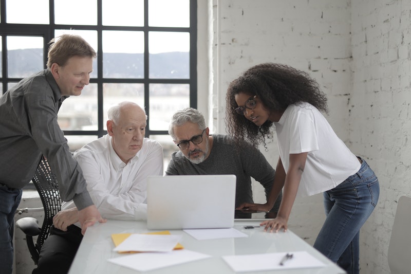 A group of four employees looking at a laptop screen