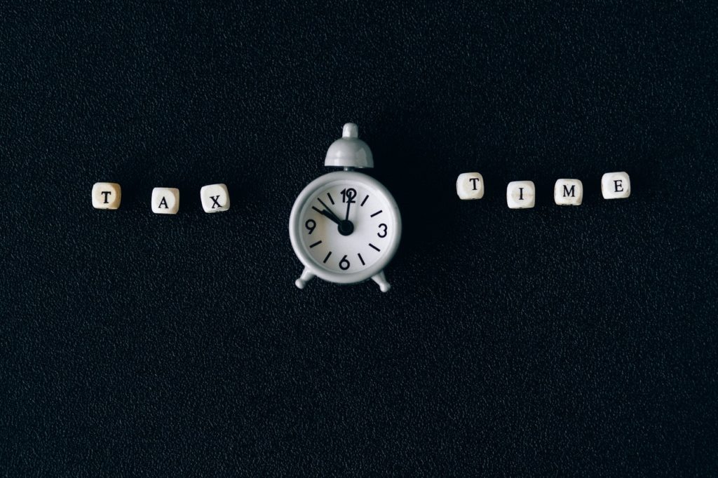 An old fashioned alarm clock with the words " Tax Time" in block letters