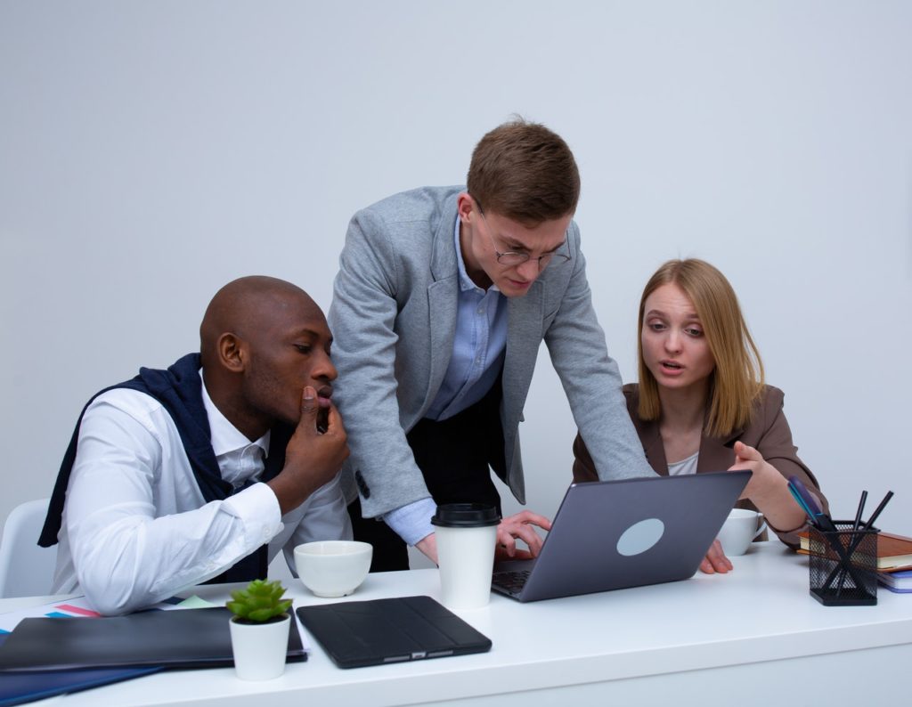 Two men and one woman accountant involved in a discussion around a laptop