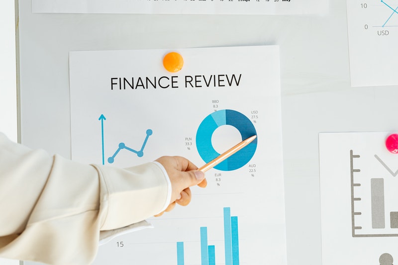 A lady pointing with a pencil to a Finance Review chart