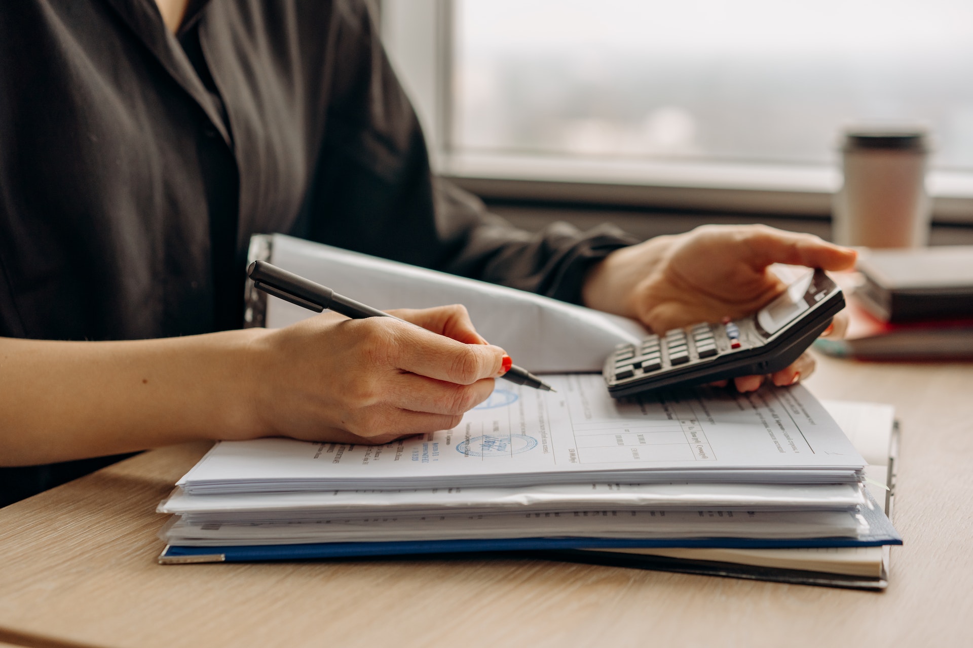 An accountant writing notes on invoices in a file