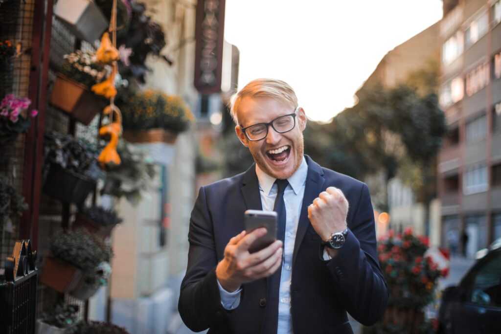 An ecstatic man holding his mobile phone