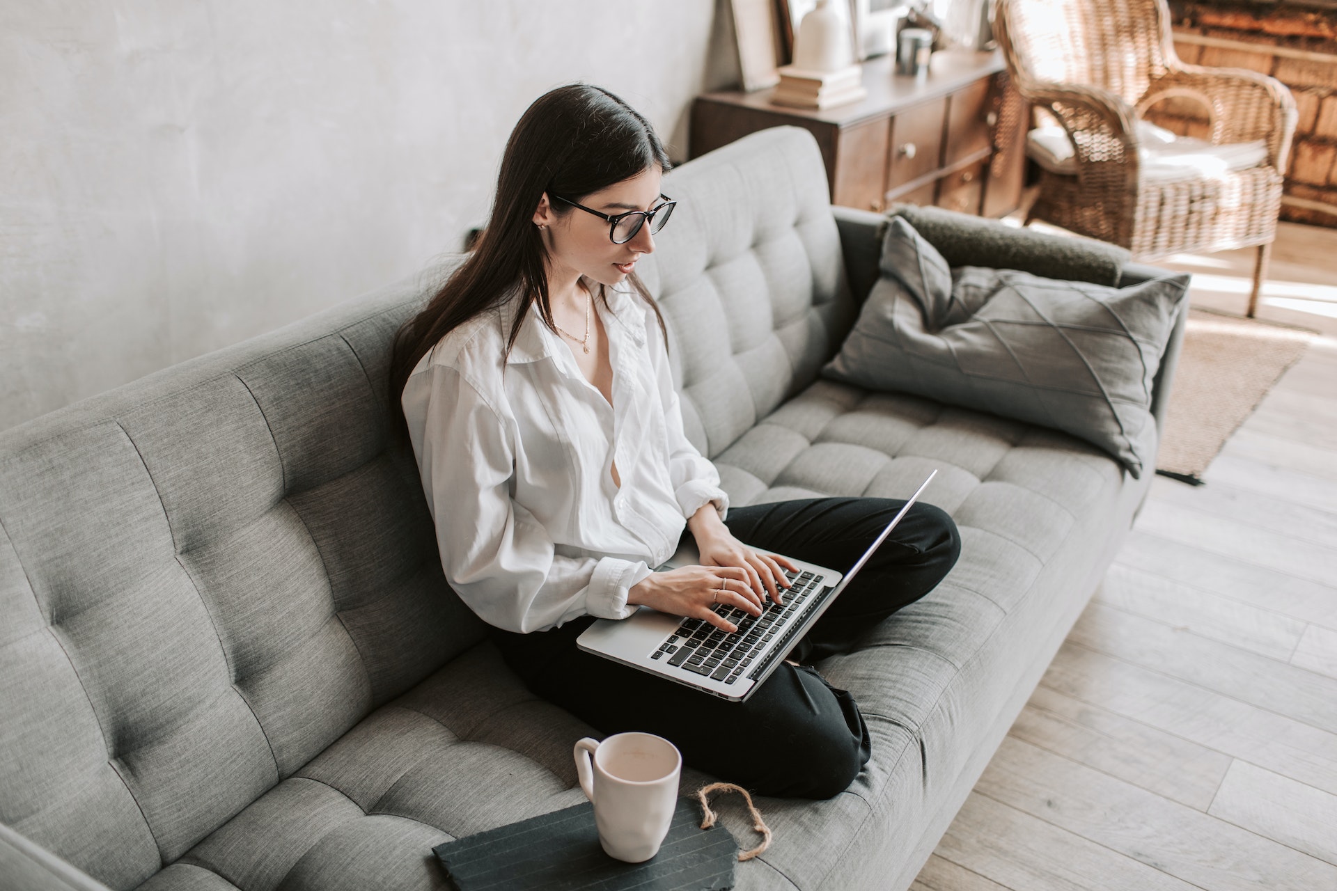 A lady sitting on the couch with her laptop, resarching Expensify competitors