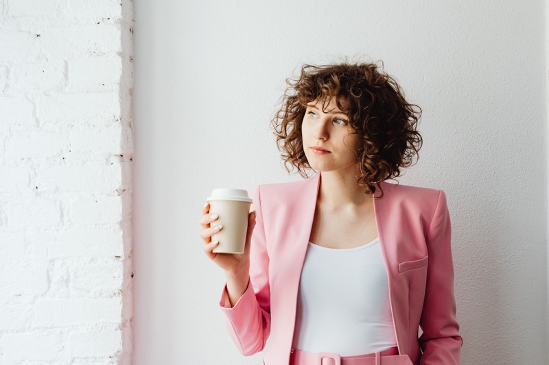 employee in pink suit holding cup of coffee