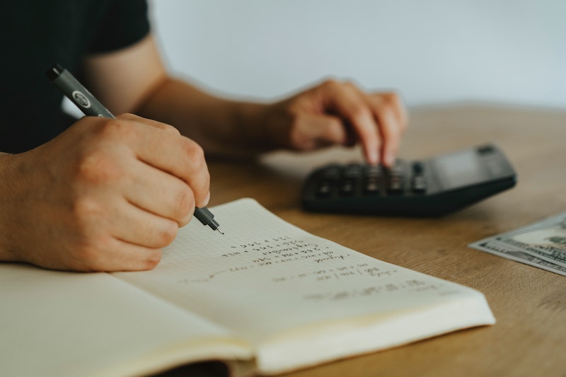 person writing on white notebook