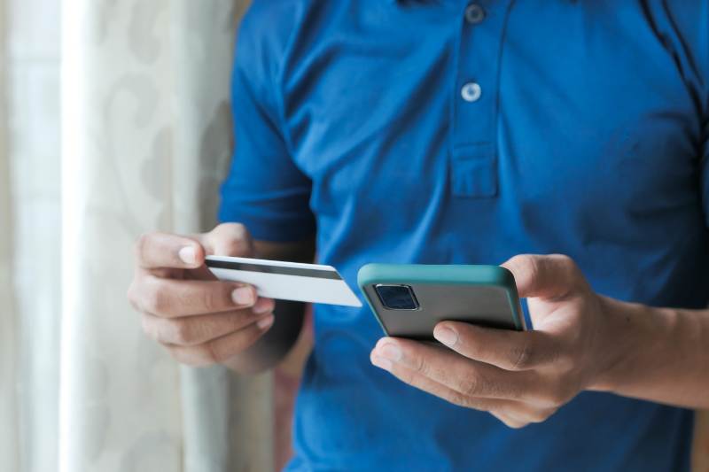 man in blue shirt holding a phone and card