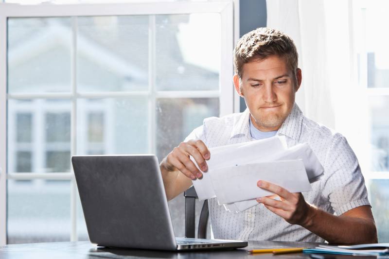 man holding a paper in front of a laptop