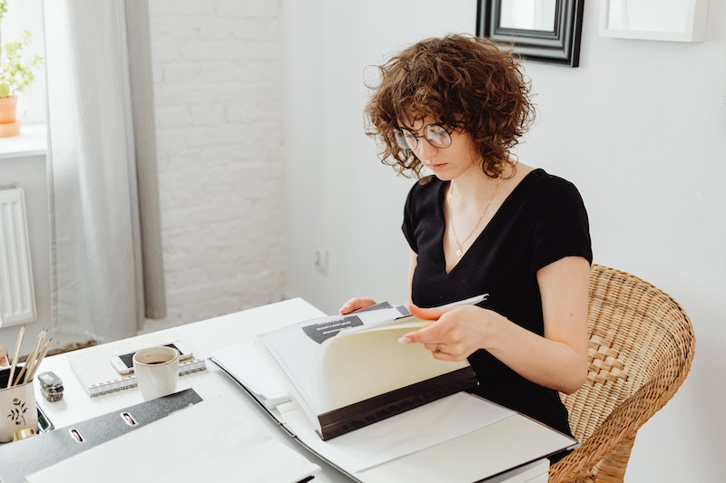 Woman in Black V-Neck Shirt Reading Documents 