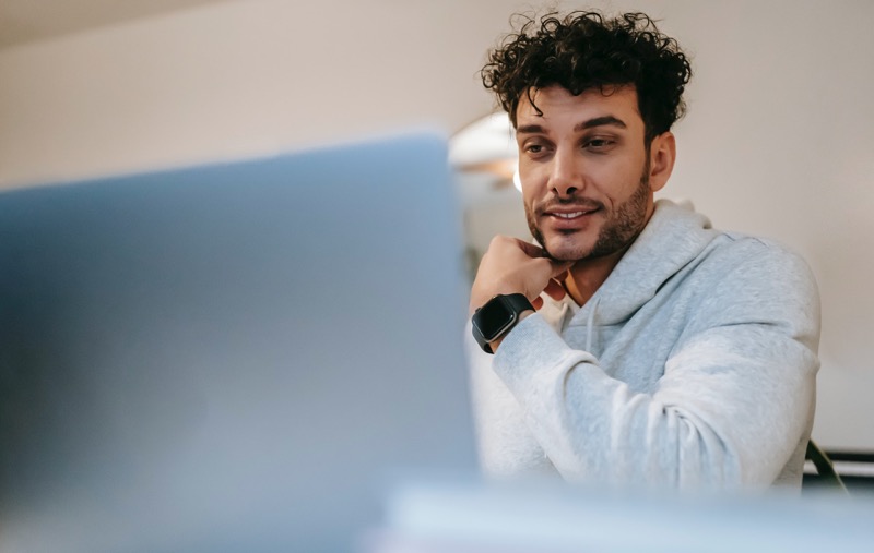 man in long sleeve looking at his laptop