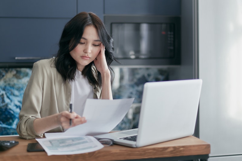 woman holding paper in front of a laptop