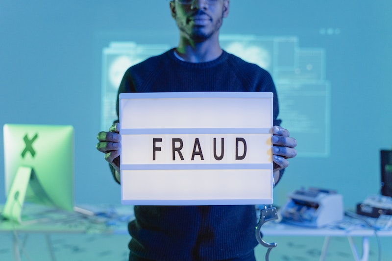 man holding letterboard with fraud text