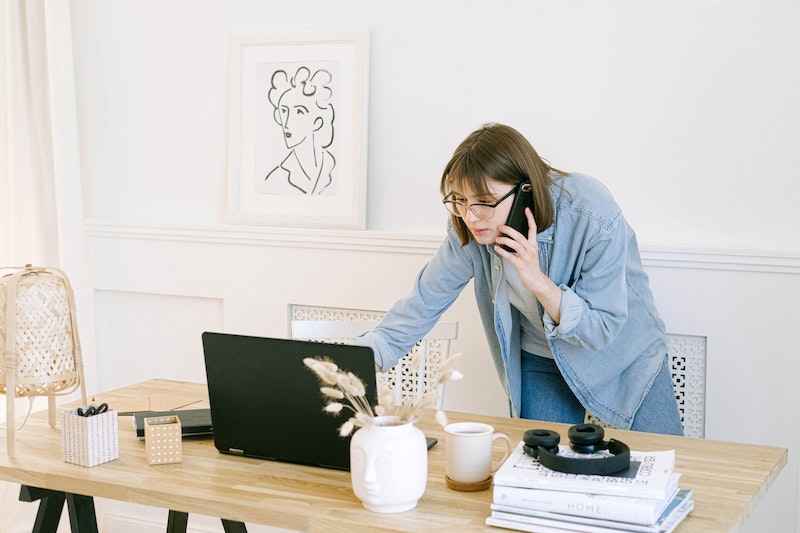 woman talking on her mobile phone while looking at laptop