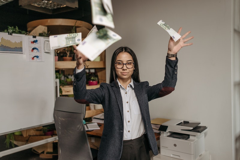 woman in business attire throwing money in the office