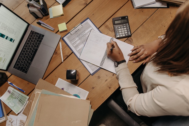 person in white long sleeve writing in a paper