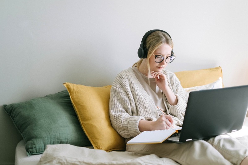 woman sitting in the sofa while working in her laptop