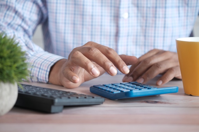 man wearing long sleeve using a calculator