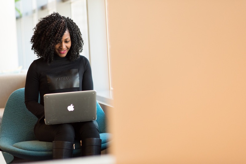 woman smiling while looking at her laptop