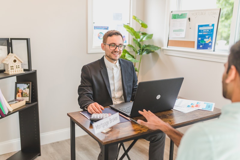 man sitting while talking in front of another worker