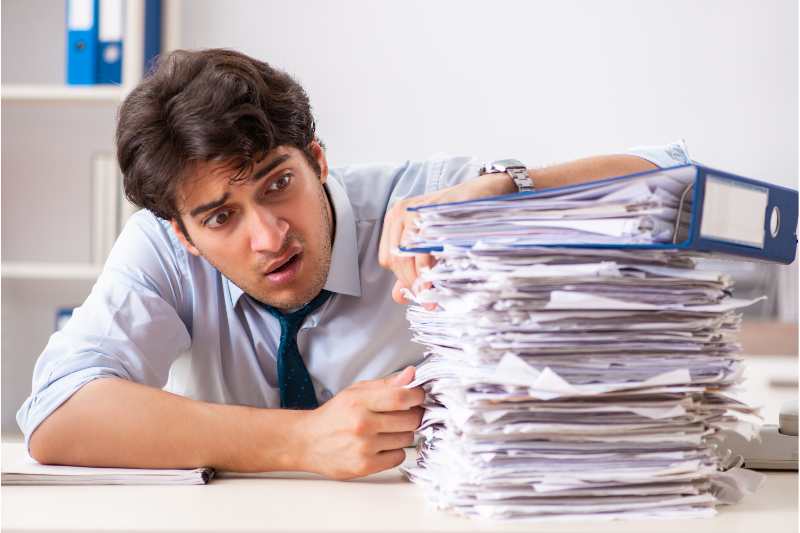 man looking at huge pile of paper stock 