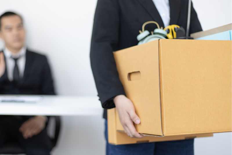 male office worker leaving office carrying a box