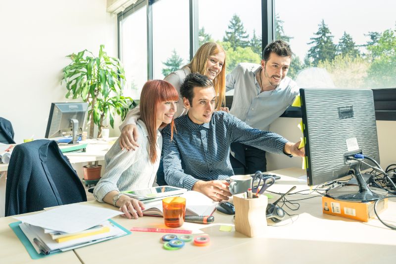 marketing team smiling in front of the computer