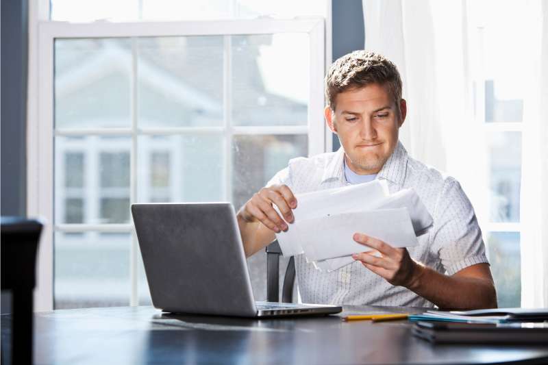 man checking bills in front of laptop