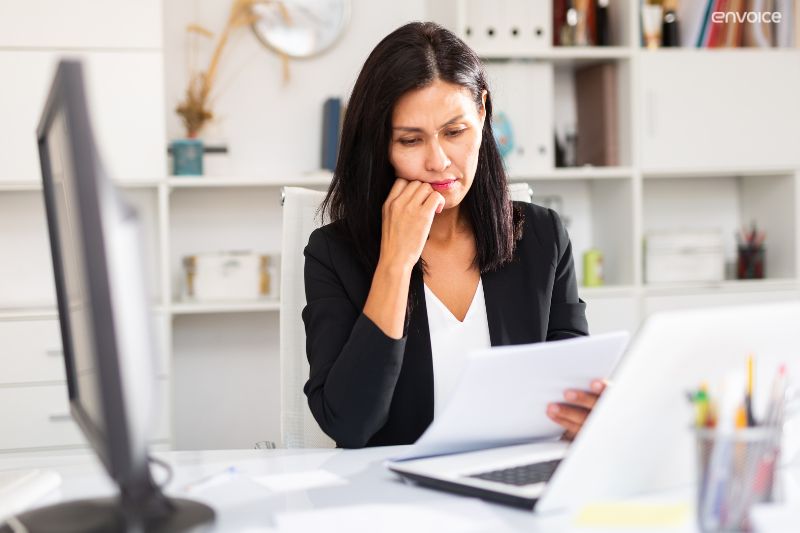 Businesswoman reviewing documents, highlighting time-saving benefits of automated invoice processing solutions.